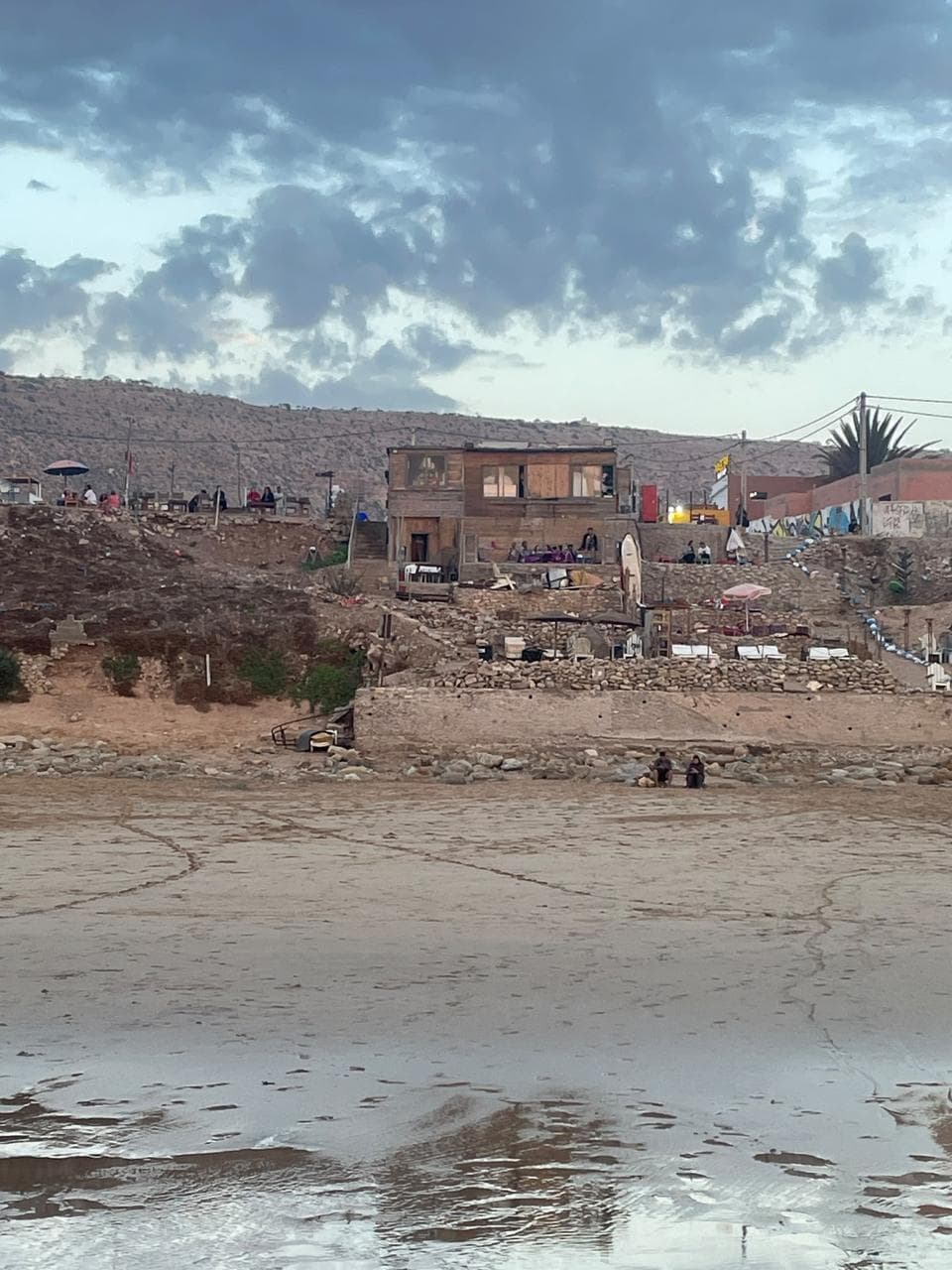 Beach shacks on the cliffs above the sand in soft evening light