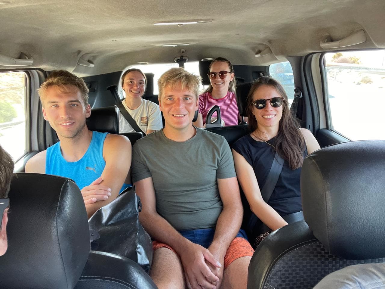 Smiling camp crew riding together in the van to the surf spot